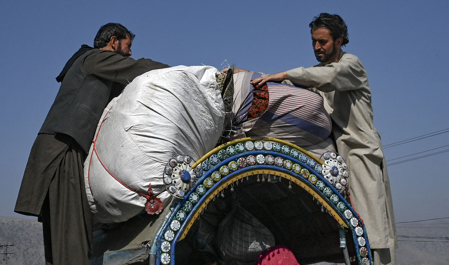 Afghan nationals traveling with their families secure their belongings on a vehicle in Jamrud area of Khyber district, some 30 Km west of Peshawar on October 6, 2023, as they return to Afghanistan following Pakistan's government decision to expel people illegally staying in the country. (AFP)