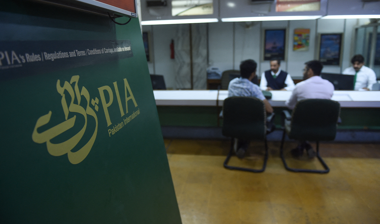 Staff of Pakistan International Airlines (PIA) talk with passengers at a PIA office in Karachi on February 27, 2019. (AFP/File)