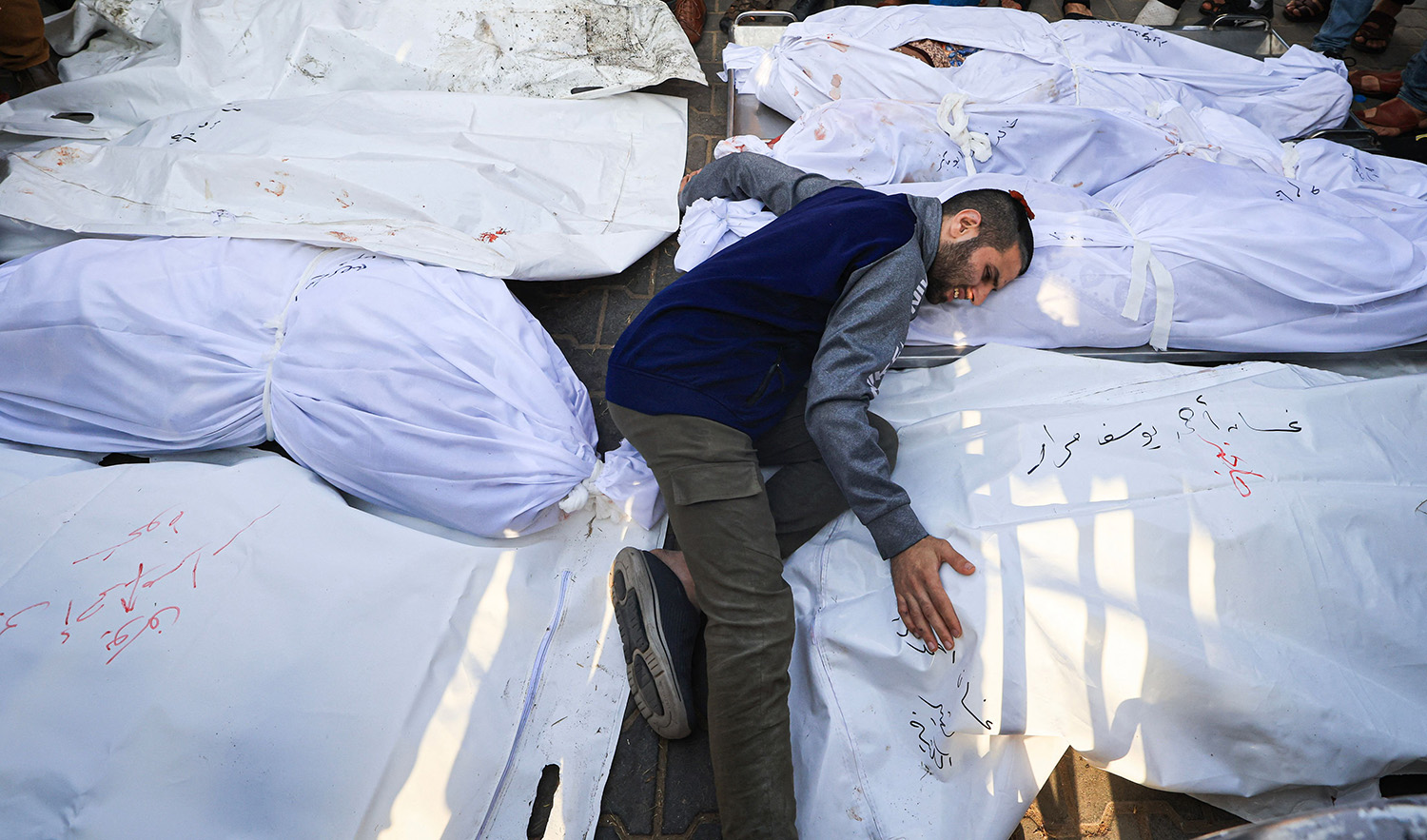A relative mourns by the bodies of members of the Abu Morad family who died following Israeli strikes earlier, during their funeral in Khan Yunis in the southern Gaza Strip on October 24, 2023. (AFP)