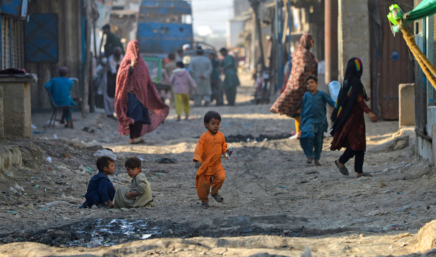 Afghan children sit along a street in the refugee camp in Karachi, Pakistan on October 26, 2023. (AFP)