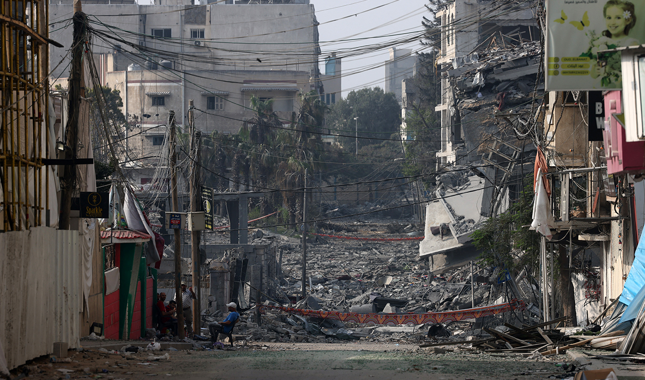 Graphic content / TOPSHOT - A man sits in front of buildings destroyed by Israeli strikes in Gaza City on October 28, 2023. (AFP/File)