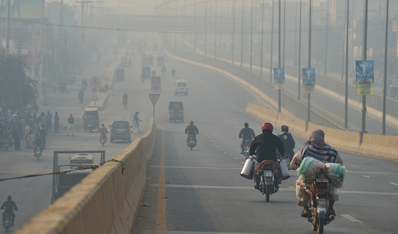 Commuters make their way amid heavy smog along a road in Multan on February 16, 2023. (AFP/File)