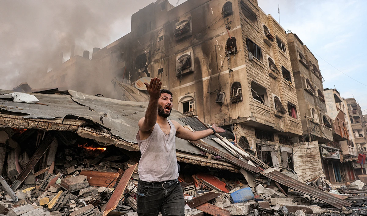 A man reacts outside a burning collapsed building following Israeli bombardment in Gaza City on October 11, 2023. At least 30 people have been killed and hundreds wounded as Israel pounded the Gaza Strip with hundreds of air strikes overnight, a Hamas government official said on October 11. (AFP)