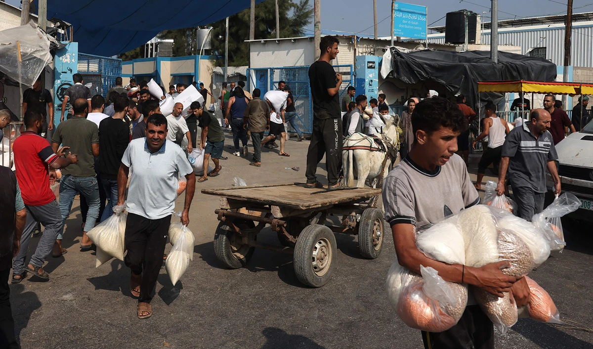 Palestinians collect bags of dried pulses from a UN-run aid supply center in Deir al-Balah on October 28, 2023. (AFP)