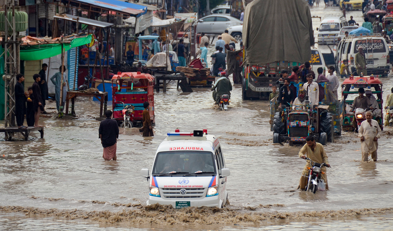 Commuters wade through a flooded street after heavy monsoon rains in Jaffarabad district of Balochistan province on July 27, 2023. (AFP/File)