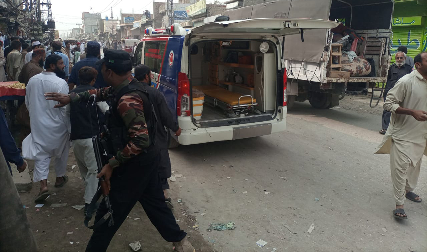 A police officer keeps people away from a blast site in Dera Ismail Khan, Pakistan, after two separate attacks on security convoys killed seven people and left 23 others wounded. (Photo courtesy: Rescue 1122)