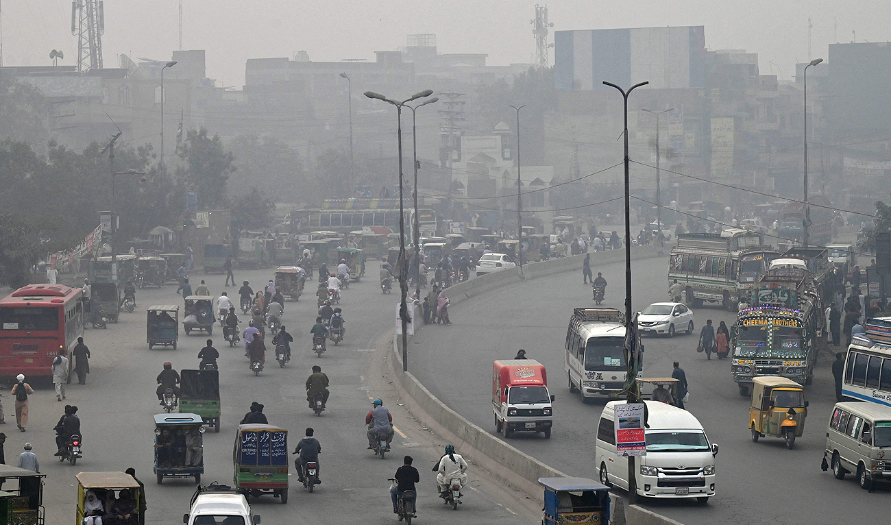 Commuters make their way through a busy street amid smoggy conditions in Lahore on November 7, 2023. (AFP)