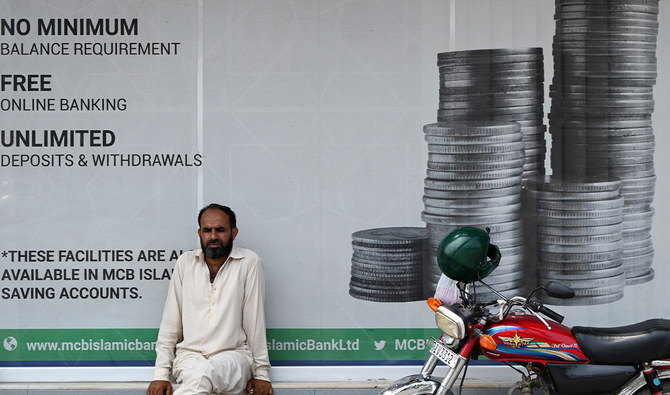 A man sits outside a bank along a street in Rawalpindi, Pakistan on July 15, 2023. (AFP/File)