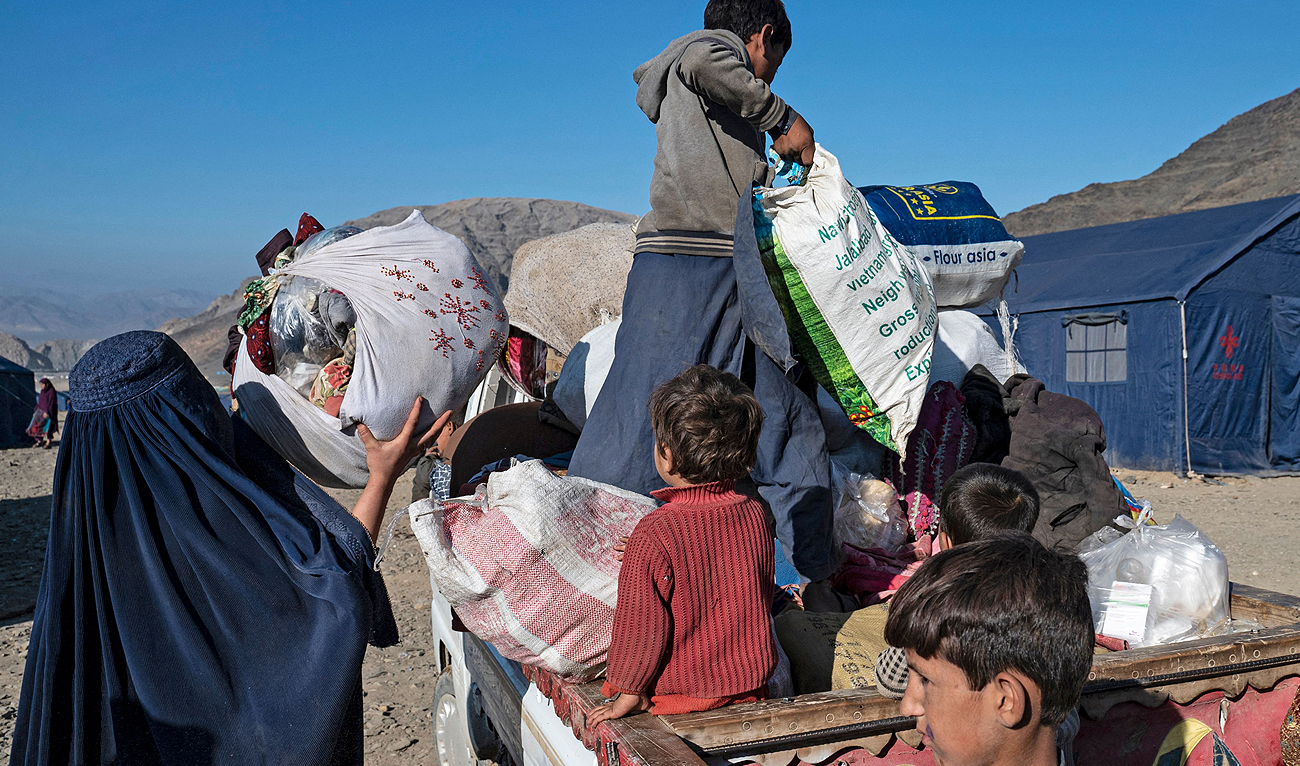 In this photograph taken on November 12, 2023, Afghan refugee Shazia (L), mother to three children, loads her belongings onto a truck heading to Jalalabad, at a makeshift camp near the Afghanistan-Pakistan Torkham border in Nangarhar province, days after their deportation from Pakistan. (AFP)