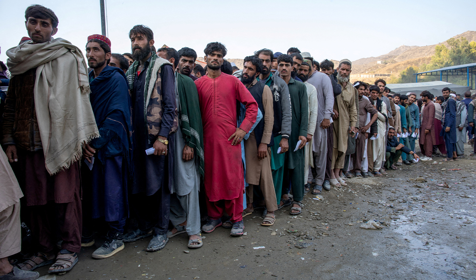 Afghan nationals stand in a queue as they wait to undergo screening to access humanitarian aid at the Torkham border crossing between Pakistan and Afghanistan, October 30, 2023. (The Norwegian Refugee Council/REUTERS/File)