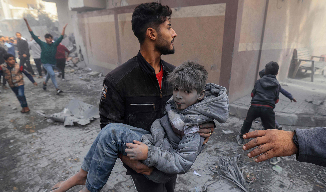 A man carries a child injured in an Israeli strike on Rafah in the southern Gaza Strip on November 20, 2023. (AFP)