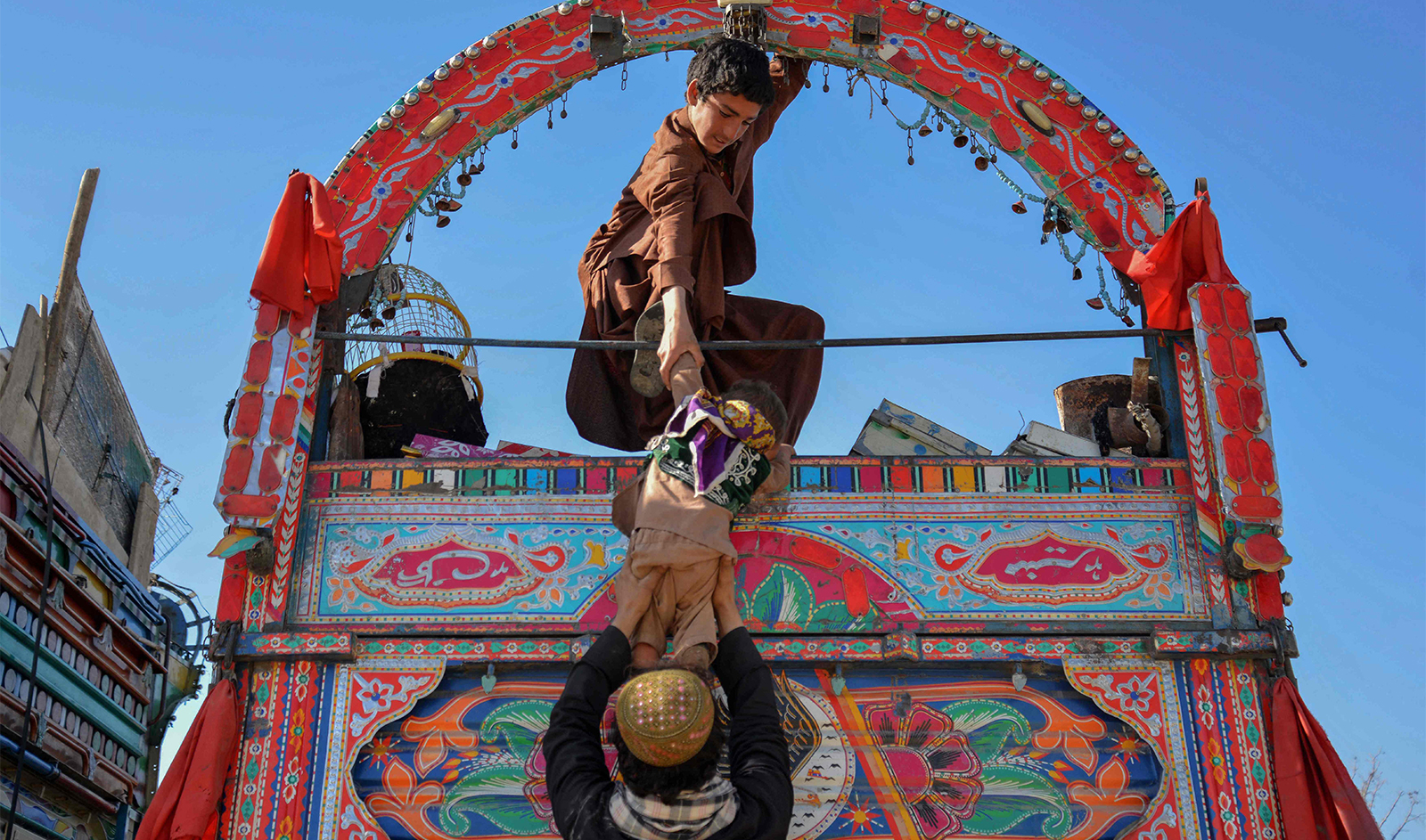 Afghan refugees help a child to get down from a truck upon their arrival from Pakistan, at a registration centre near the Afghanistan-Pakistan border in the Spin Boldak district of Kandahar province on November 20, 2023. (AFP/File)