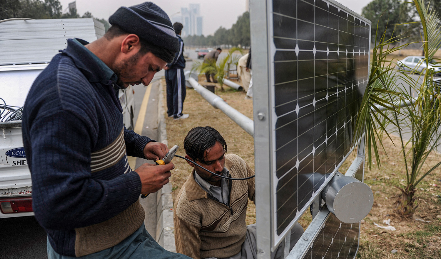 Pakistani workers prepare solar energy light panels on a road divider in Islamabad, Pakistan on February 2, 2014. (AFP/File)