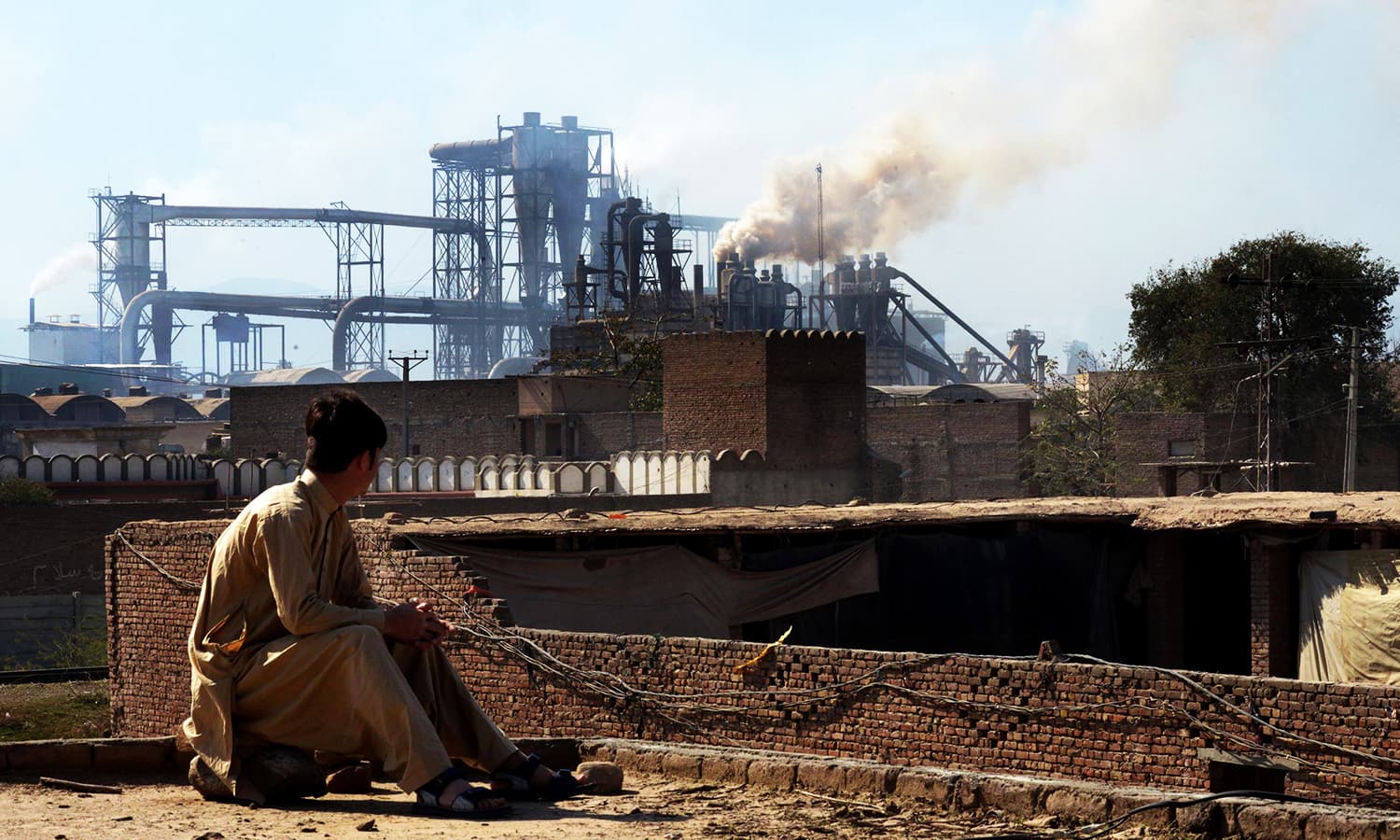 This photograph taken on February 25, 2017, shows a Pakistani worker watching smoke rising from factories on the outskirts of the northwestern city of Peshawar. (AFP/File)