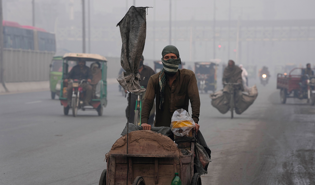 A corn seller pushes his hand cart as heavy fog reduces visibility, in Lahore, Pakistan, Friday, Nov. 24, 2023. (AP)