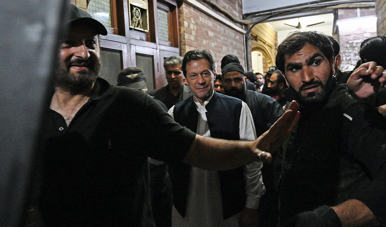 Security personnel use a bullet proof shield to protect former Pakistan's Prime Minister Imran Khan as he leaves after appearing at the high court in Lahore on March 17, 2023. (AFP/File)
