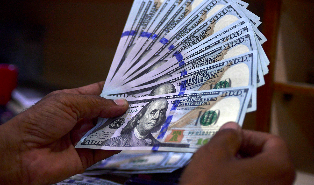 A foreign currency dealer counts US dollar notes at a currency market in Karachi on July 19, 2022. (AFP/File)