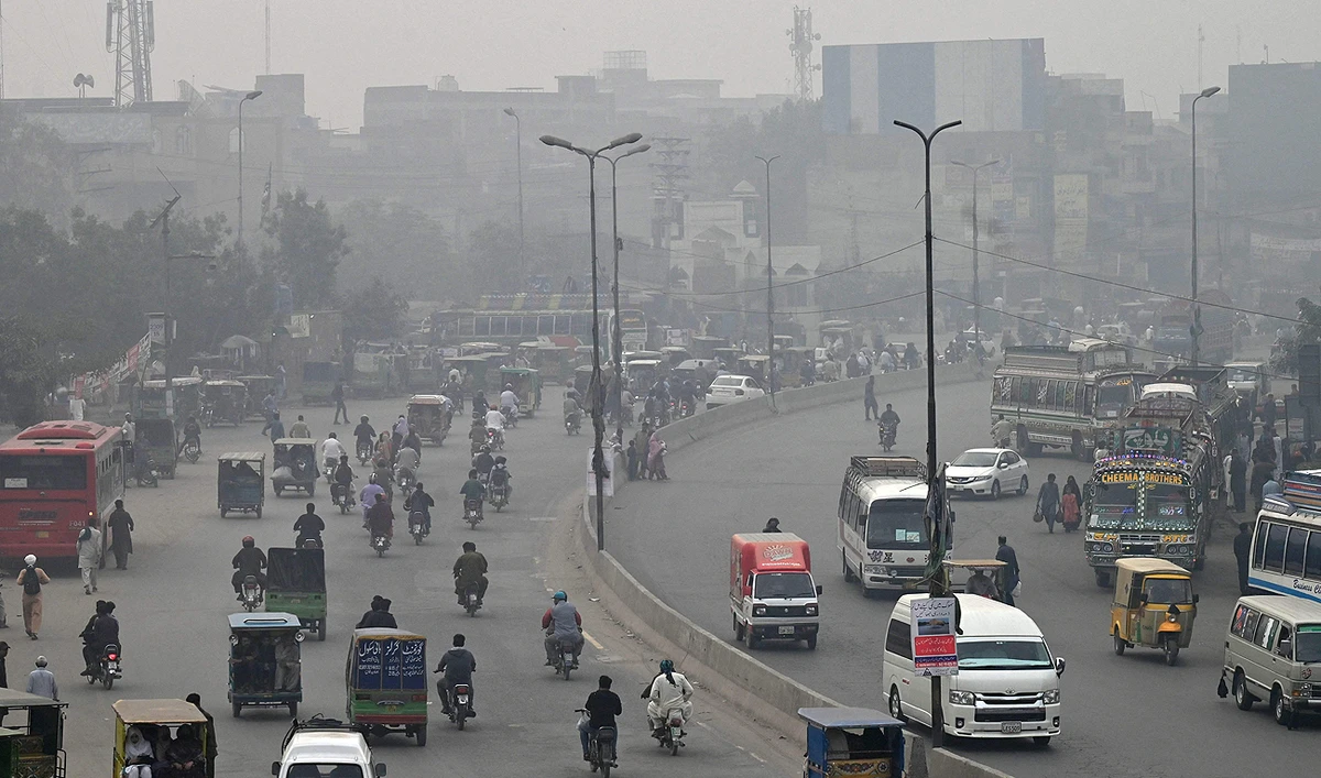 Commuters make their way through a busy street amid smoggy conditions in Lahore on November 7, 2023. (AFP)