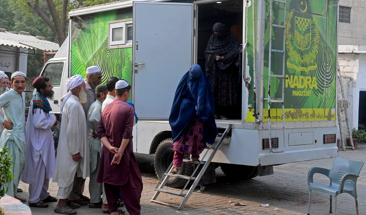 Afghan burqa-clad women refugees walk out of a National Database and Registration Authority (NADRA) van after their data verification, at a police station in Karachi on November 8, 2023. (AFP/File)