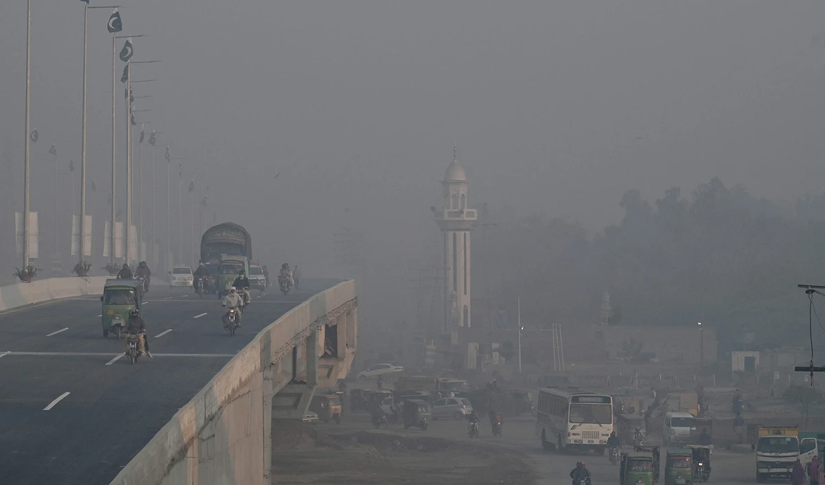 Commuters make their way along a street amid smog in Lahore, Pakistan, on November 17, 2023. (AFP)