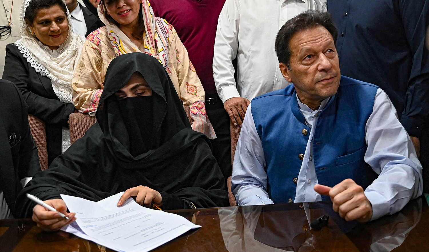 Pakistan's former Prime Minister, Imran Khan, right, along with his wife Bushra Bibi (L) looks on as he signs surety bonds for bail in various cases, at a registrar office in the High court, in Lahore on July 17, 2023. (AFP/File)