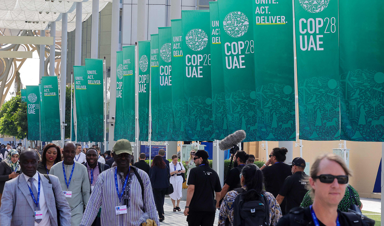 Participants walk past banners at the COP28 United Nations climate summit in Dubai, UAE on December 3, 2023. (AFP)