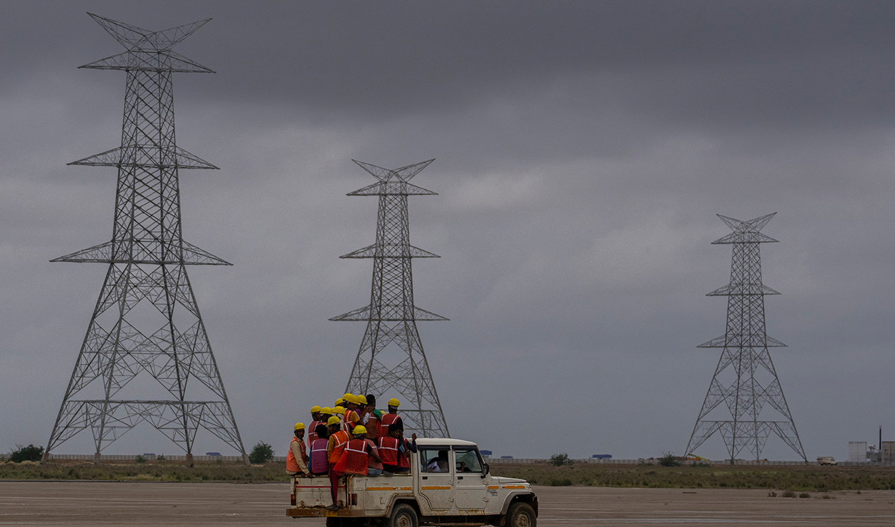Workers travels in a vehicle toward the construction site of Adani Green Energy Limited's Renewable Energy Park in the salt desert of Karim Shahi village, near Khavda, Bhuj district near the India-Pakistan border in the western state of Gujarat, India, Thursday, Sept. 21, 2023. (AP)