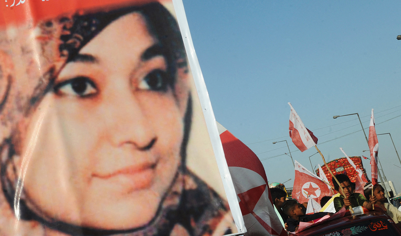 Supporters of US-detained Pakistani woman Aafia Siddiqui carry flags and placards with her portrait during an anti-US demonstration in Karachi on March 28, 2010. (AFP/File)