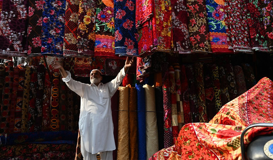 A Pakistani shopkeeper hangs fabric at his shop in a market in Lahore on September 16, 2019. (AFP/File)