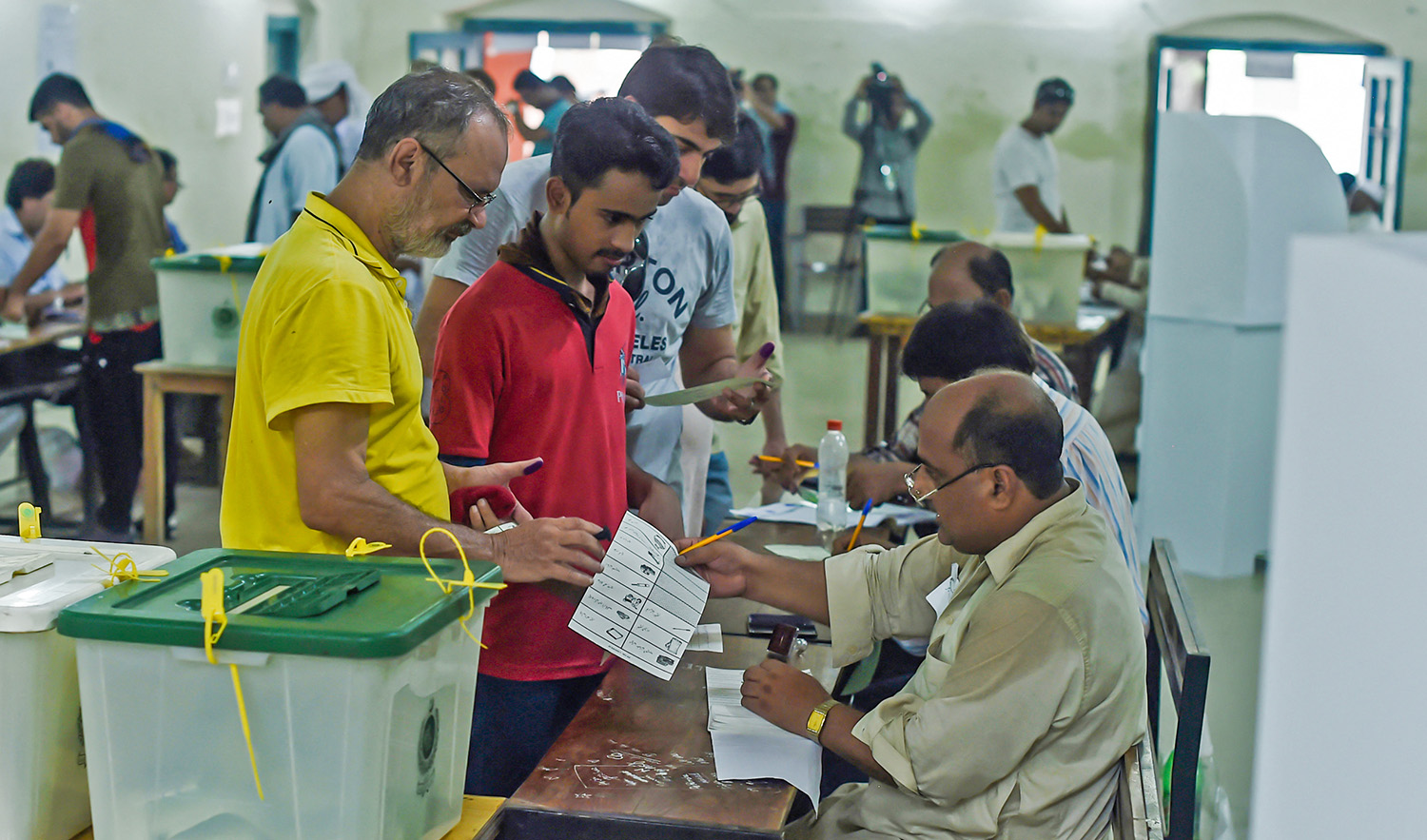 Pakistani men line up as election officials check their ballot papers during voting in Pakistan's general election at a polling station in Lahore on July 25, 2018. (AFP/File)