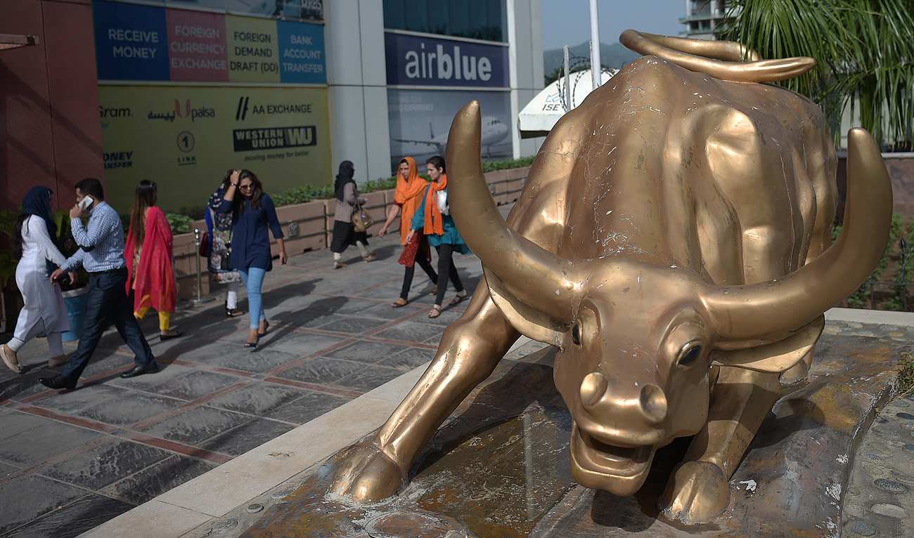 In this file photo, taken on October 9, 2018, Pakistani pedestrians walk past a bronze bull statue outside the Pakistan Stock Exchange (PSE) building in Islamabad. (AFP/File)