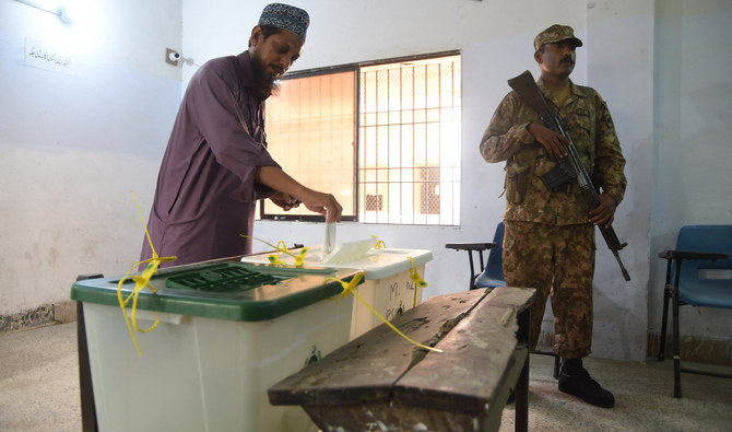 A Pakistani man casts his vote as a soldier stands guard at a polling station during Pakistan's general election in Karachi on July 25, 2018. (AFP/File)