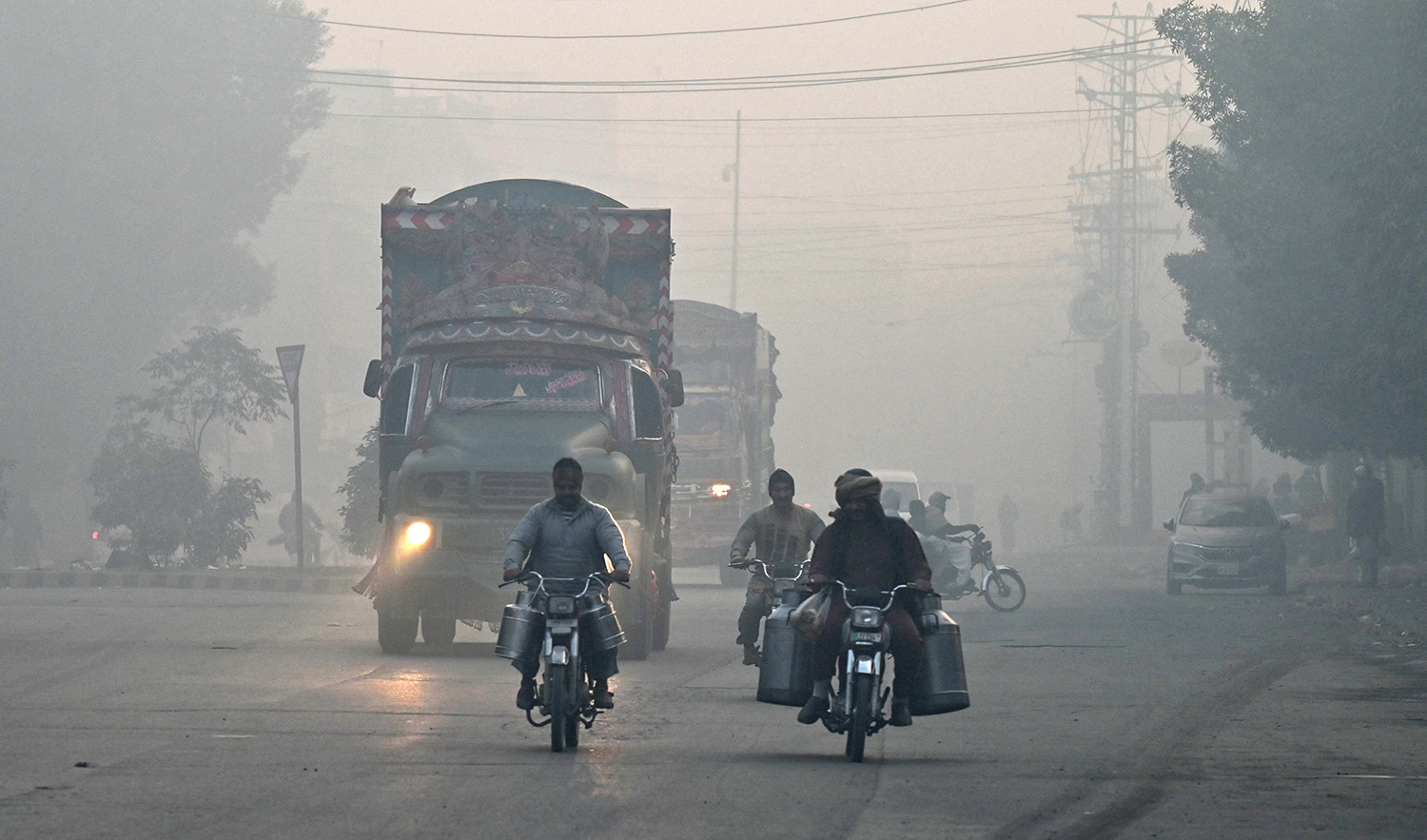 Commuters make their way along a street amid dense smog in Lahore, Pakistan on December 4, 2023. (AFP)