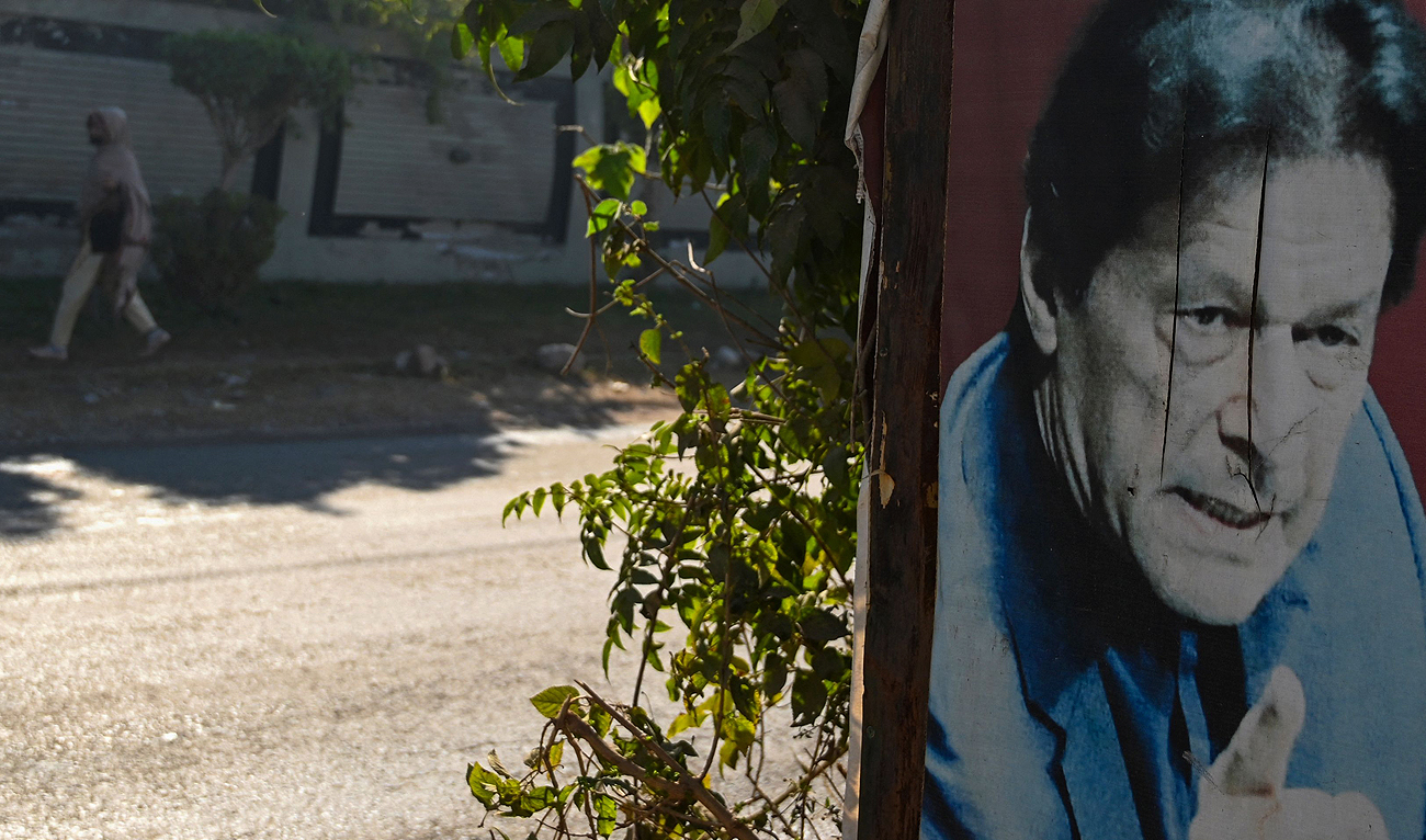 A woman walks past a poster of Pakistan's former prime minister Imran Khan near his Banigala residence, in Islamabad on December 23, 2023. (AFP)