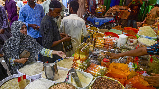 Customers bargain as they buy cereals and legumes at a shop in Karachi on June 8, 2023. (AFP/File)