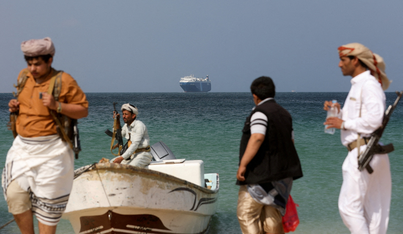Armed men stand on the beach as the Galaxy Leader commercial ship, seized by Yemen's Houthis last month, is anchored off the coast of Al-Salif, Yemen, on December 5, 2023. (REUTERS)