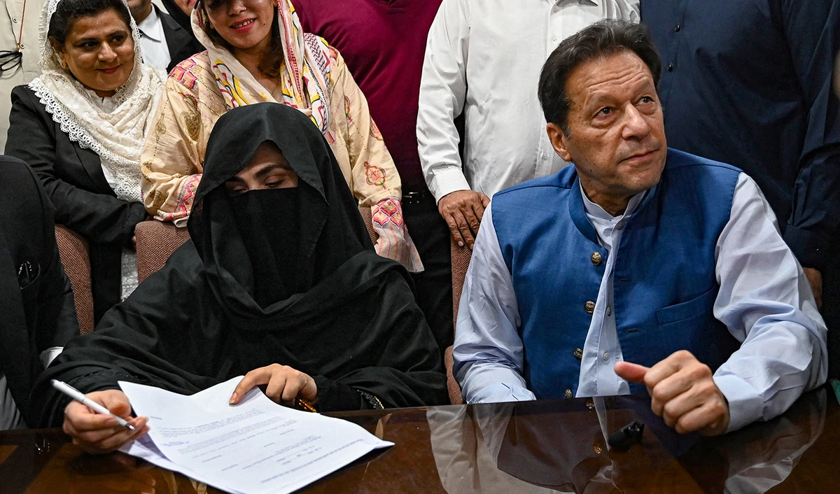 Pakistan's former Prime Minister, Imran Khan, right, along with his wife Bushra Bibi (L) looks on as he signs surety bonds for bail in various cases, at a registrar office in the High court, in Lahore on July 17, 2023. (AFP/File)
