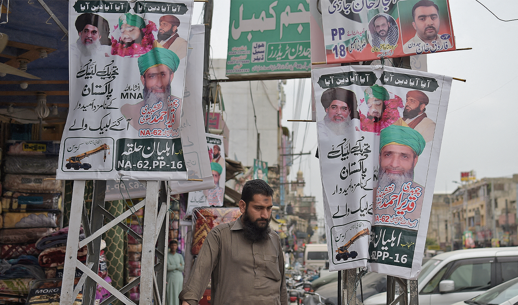 In this picture taken on July 28, 2018, a Pakistani man walks past election posters of one of the candidates of Sunni Muslim religious party Tehreek-e-Labbaik Pakistan (TLP) in Rawalpindi. (AFP/File)