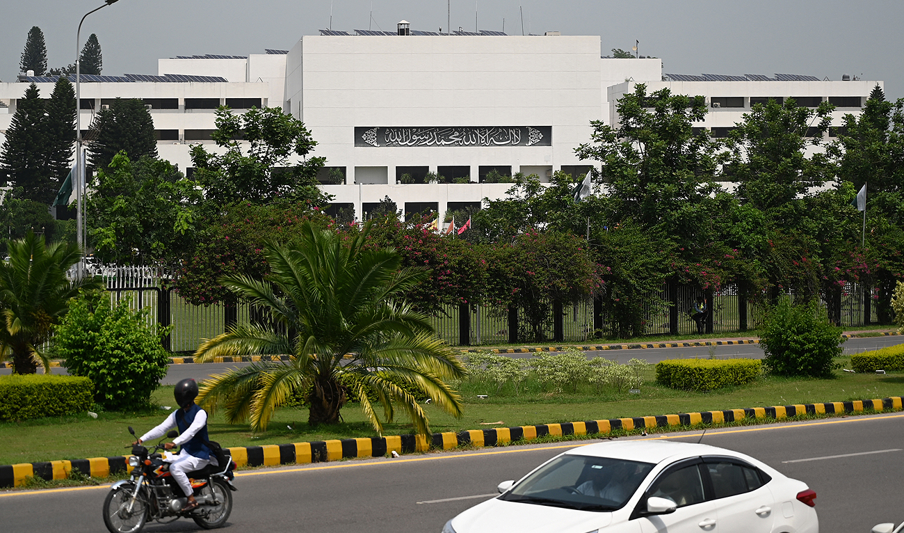 In this file photo, taken on August 9, 2023, commuters drive past the Parliament House building in Islamabad. (AFP/File)