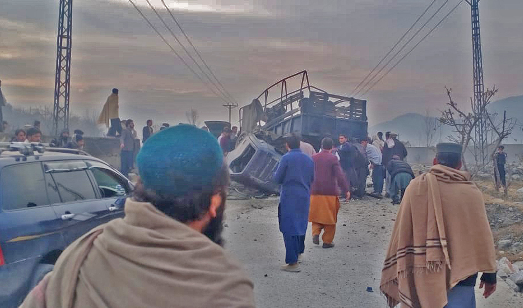 People gather next to a police vehicle targeted in a blast in Bajaur city, Pakistan, on January 8, 2024. (Rescue 1122)