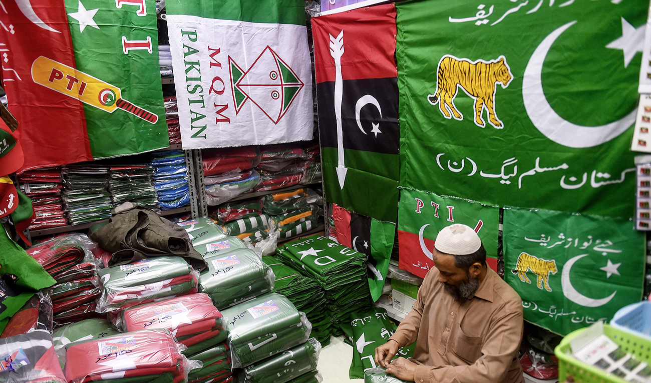 A shopkeeper arranges flags of political parties at his shop ahead of the upcoming general elections in Karachi on January 3, 2024. (AFP)