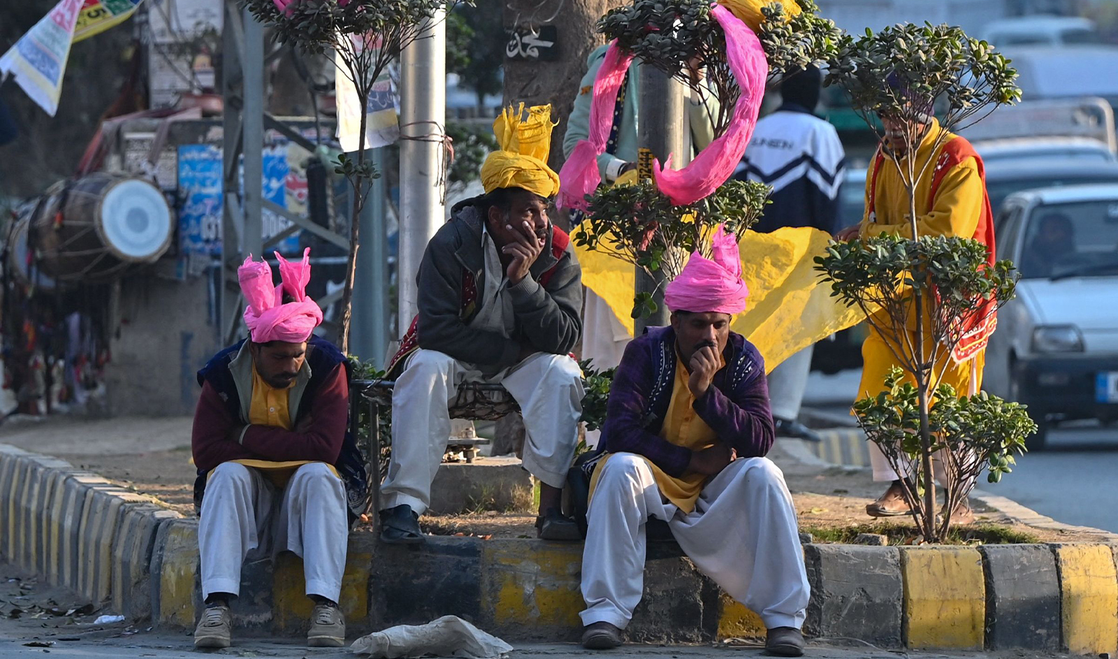 Folk dancers sit along the roadside in Islamabad, Pakistan, on January 10, 2024. (AFP)