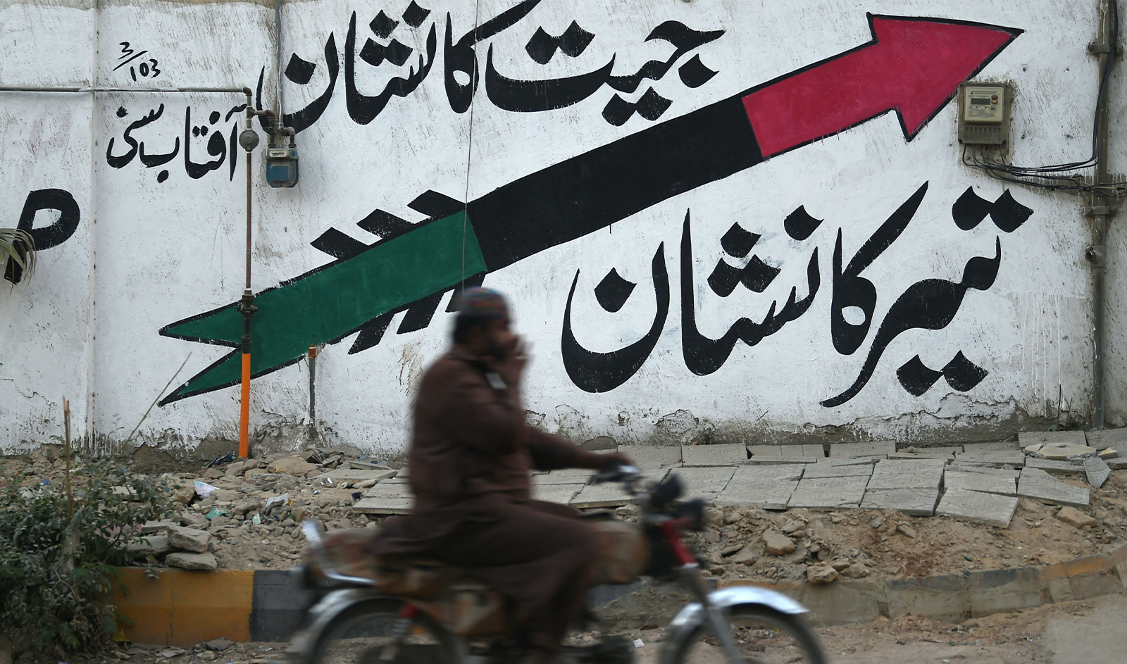 A motorcyclist rides past a wall painted with Pakistan People's Party (PPP) logo along a street in Karachi on January 12, 2024, ahead of the upcoming general elections. (AFP)
