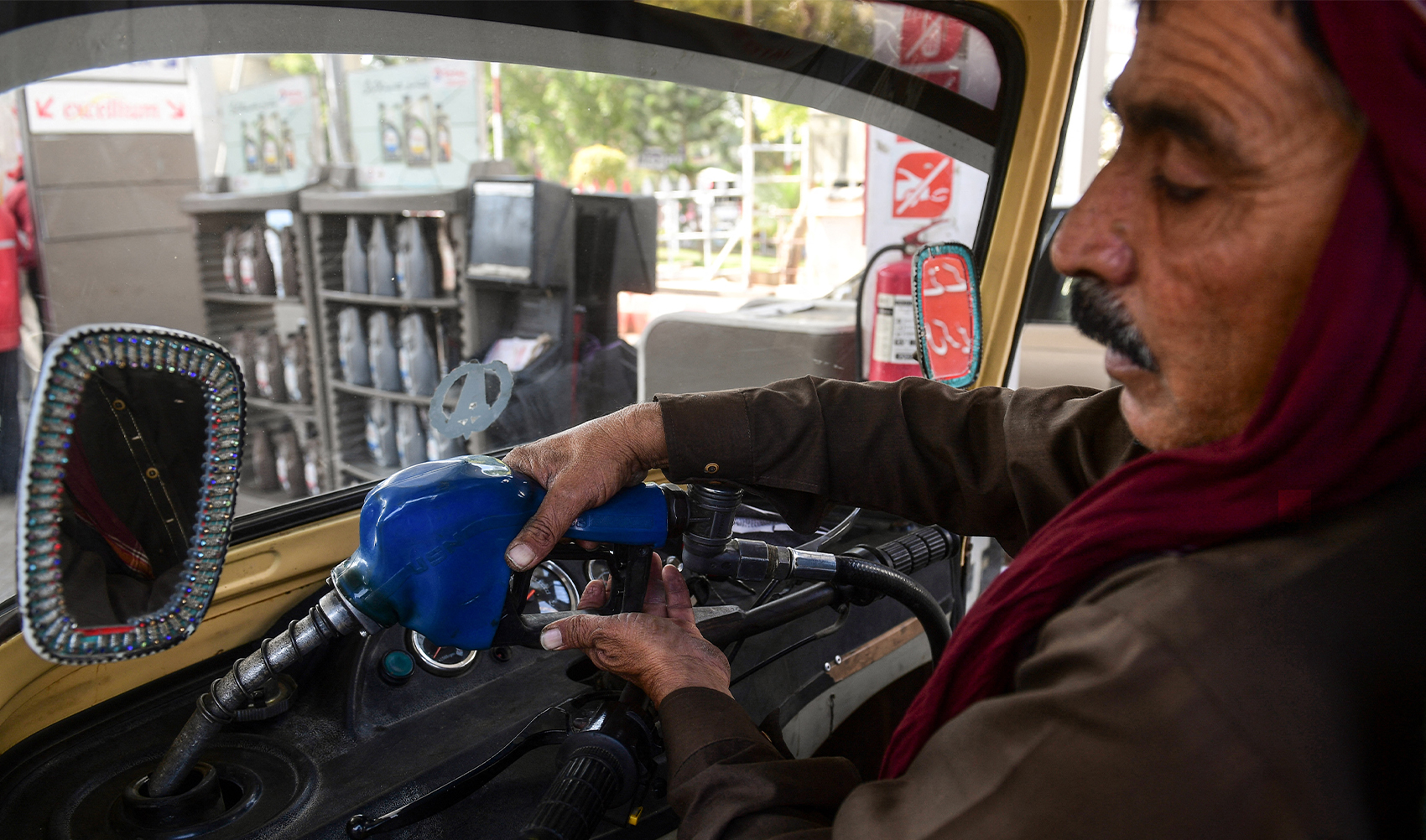 This picture taken on January 30, 2023 shows a man filling petrol in his auto-rickshaw at a gasoline station in Pakistan's port city of Karachi. (AFP/File)