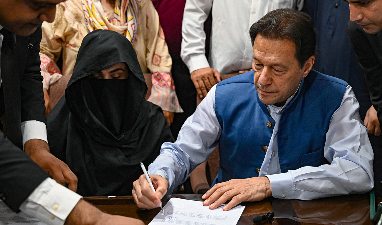 Pakistan's former Prime Minister, Imran Khan (R) along with his wife Bushra Bibi (C) signs surety bonds for bail in various cases, at a registrar office in the High court, in Lahore on July 17, 2023. (AFP/File)