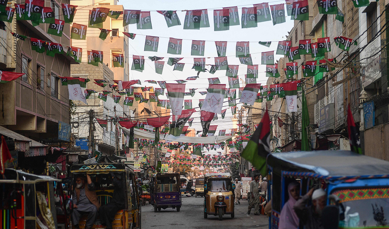 Commuters move past the Pakistan People's Party (PPP) flags hung over a street in Karachi on January 16, 2024, ahead of the country’s upcoming general elections. (AFP)