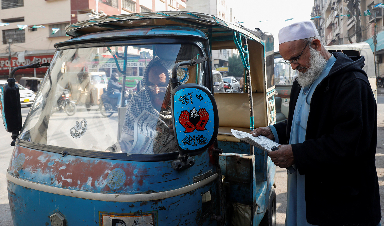 Men read newspapers, after the Pakistani foreign ministry said the country conducted strikes targeting separatist militants inside Iran, along a road in Karachi, Pakistan, on January 18, 2024. (REUTERS)