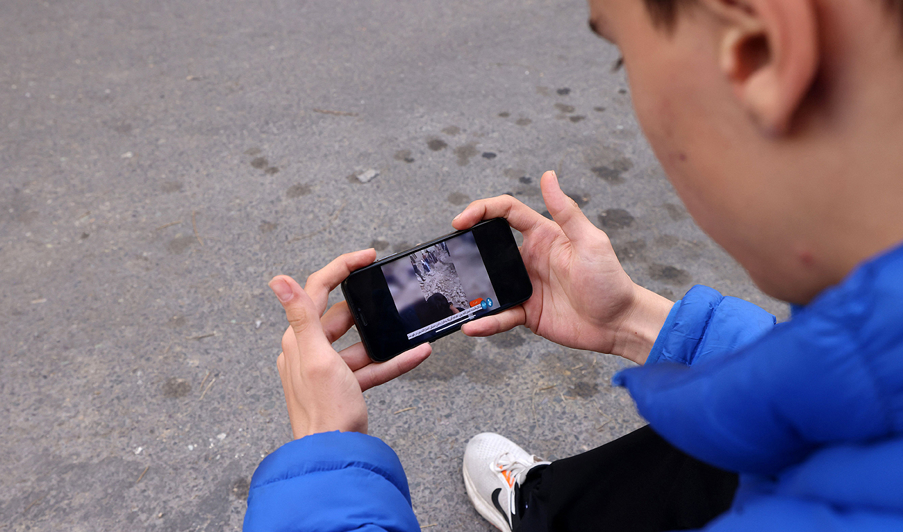 An Iranian man watches the news on his phone in a street in Tehran, on January 18 2024. Pakistan launched deadly strikes on January 18 against militant targets in Iran in apparent retaliation for Iranian air raids on its territory, further stoking tensions and prompting Tehran to summon Pakistan's envoy. (AFP)