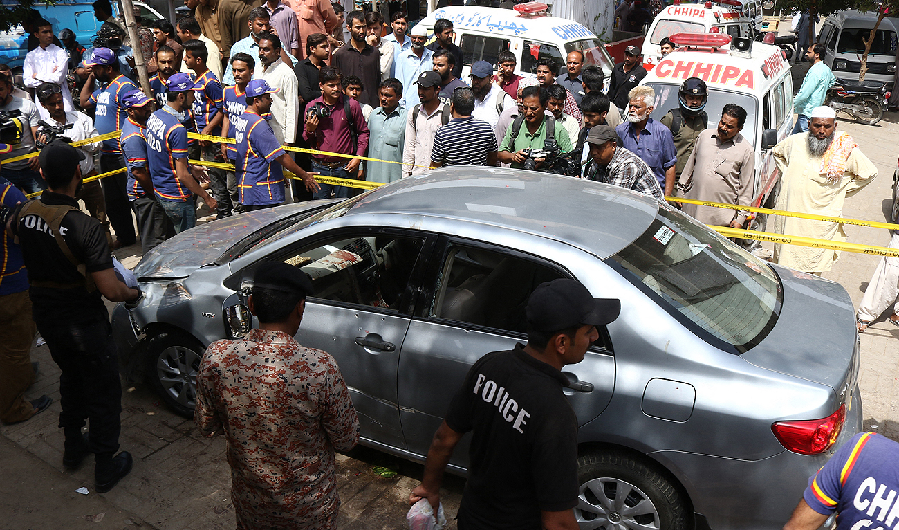 In this file photo, taken on March 22, 2019, security personnel and onlookers gather around the car of leading religious scholar Muhammad Taqi Usmani after an attack by unidentified gunmen in Karachi. At least two people were killed in the attack on March 22. (AFP/File)