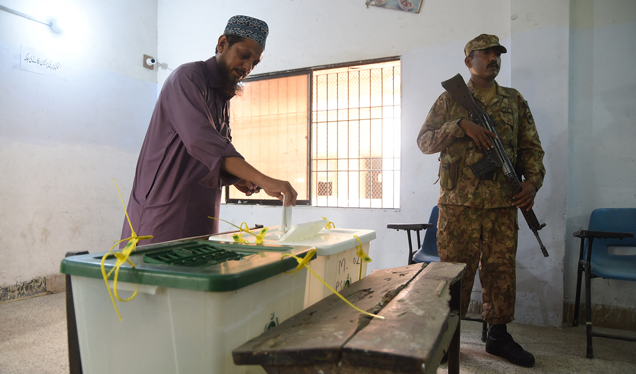 A Pakistani man casts his vote as a soldier stands guard at a polling station during Pakistan's general election in Karachi on July 25, 2018. (AFP/File)